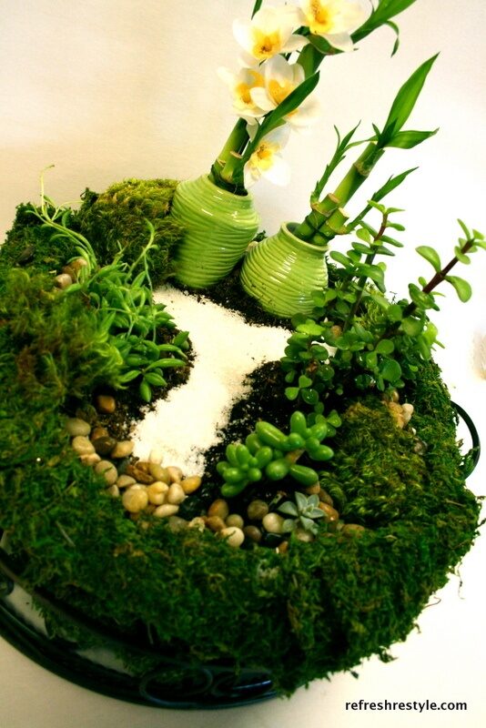 Succulent mini garden with lucky bamboo~planted in an aluminum roasting pan, then placed in a moss lined metal & glass container.  She then used moss to cover all the pan, so it looks like a mini garden in a bowl of moss.  Very creative!