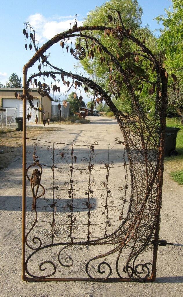 Unique garden gate using metal pipe, re bar, old fencing, barbed wire, metal table legs, rusty tin cans and vintage chandelier crystals