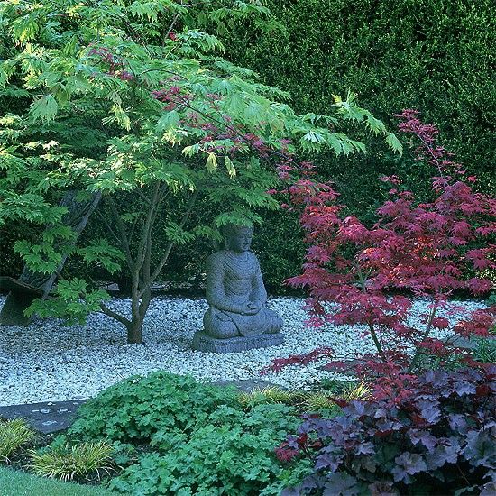 a shady courtyard of pebbles and brick paths, filled with acers, hellebores, ferns and grasses. A Buddha crafted from blue Karnataka stone, sits beneath Acer palamatum.  Peaceful