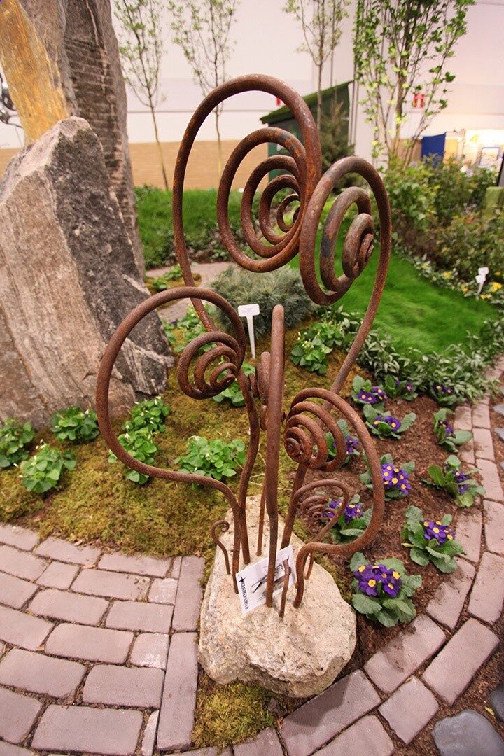 Metal landscape and garden decor creates a lovely counterpoint to the lush delicacy of plants and flowers.