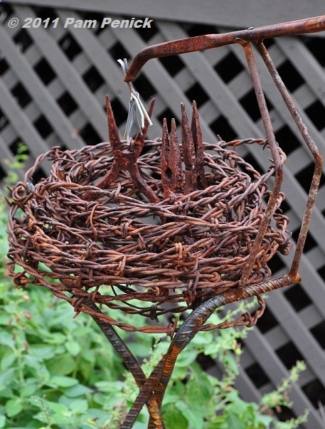 Old tool garden art: pliers become baby birds in a barbwire nest.