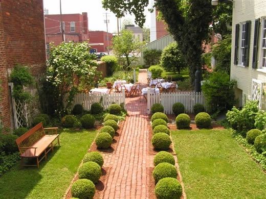Nice landscape idea for a narrow space. I like the ball shape box woods lining the brick pathway.